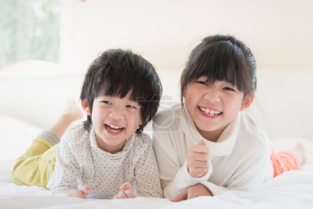 Asian children lying on white bed