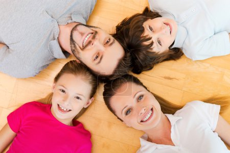 top view of happy family of four bonding to each other heads and
