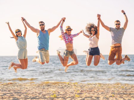 Happy young people jumping on beach