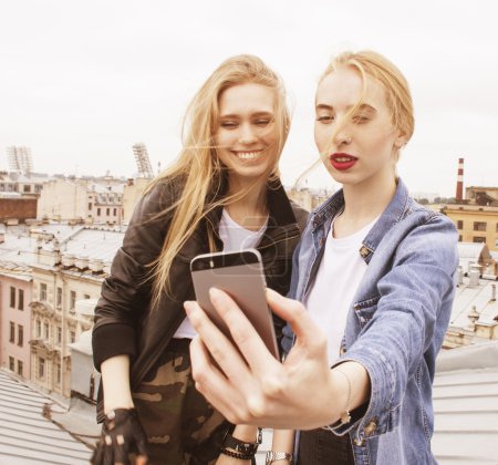 Two cool blond real girls friends making selfie on roof top, lifestyle people concept