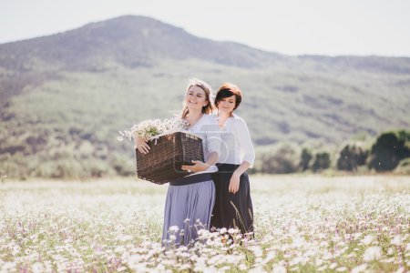 两个年轻漂亮的女模特摆姿势在洋甘菊领域