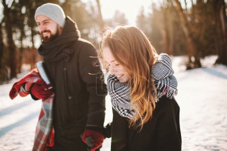 年轻的时髦夫妇在冬季森林手牵着手散步