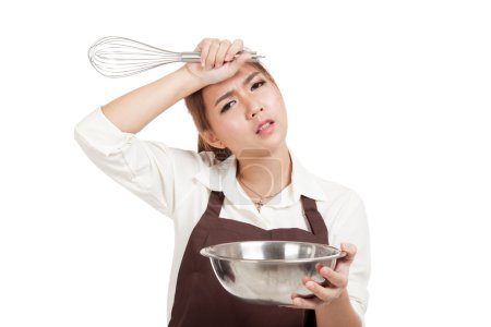 Exhausted Asian baker girl with whisk and bowl