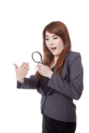 Asian businesswoman surprised use magnifying glass watching hand