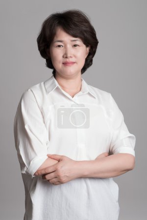 Portrait of beautiful mature woman posing against gray background