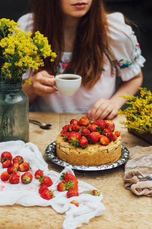 女人吃美味的自制蛋糕与 aisheny 和毛绒的草莓甜点.夏天的风格餐桌.
